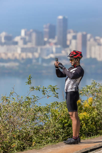 athlet biker nehmen selfie oben auf einem berg über dem stadtteil ipanema in rio de janeiro brasilien - brazil bicycle rio de janeiro outdoors stock-fotos und bilder