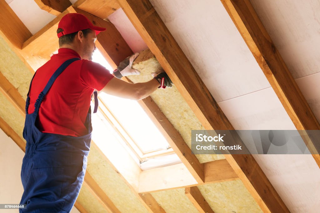 house attic insulation - construction worker installing rock wool in mansard wall Insulation Stock Photo