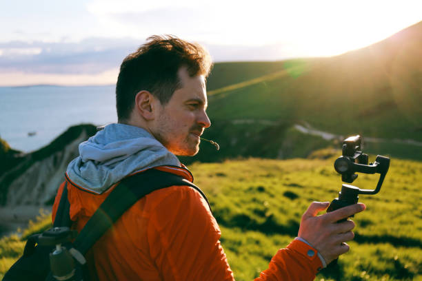 istock Young attractive man films a travel video using a hand held stabiliser and smartphone 878465148