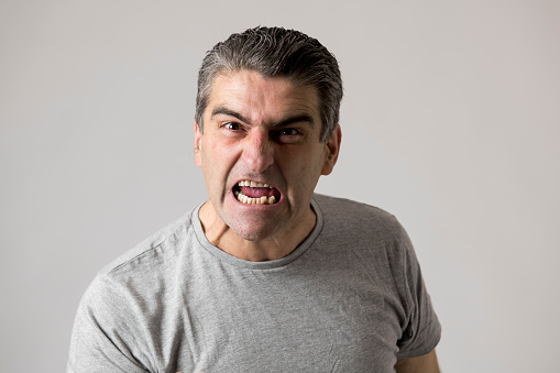 portrait of 40s to 50s white angry and upset guy and crazy furious and aggressive face expression nagging and complaining isolated on grey background in emotions and feelings concept