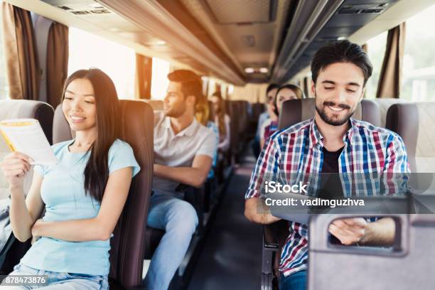 El Chico De La Camisa Se Sienta En El Autobús Y Mira Algo Sobre Su Tableta Gris Él Sonríe Foto de stock y más banco de imágenes de Autobús