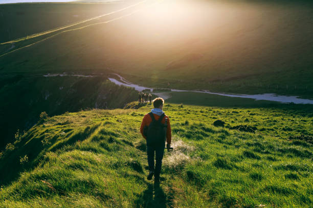 istock Young man in red jacket walking on a path towards Durdle Door alongside Jurassic Coast, Dorset, UK 878474034