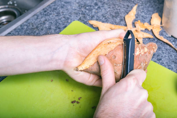 mâle main épluchage de patates avec un épluche-légumes - root vegetable raw potato human skin root photos et images de collection
