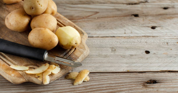 istock Raw potatoes with a vegetable peeler 878481610