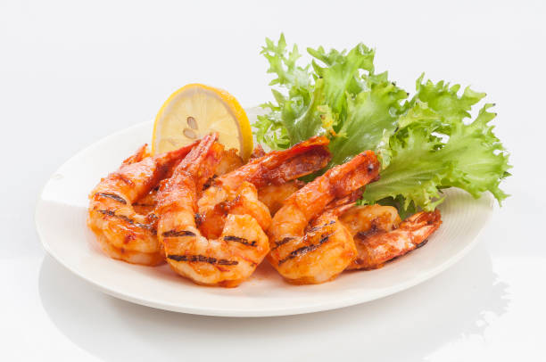 Grilled Jumbo headless shrimp with tikka marinade with lemon tomato and lettuce Creative Seafood photography on white plate on white background persian gulf countries stock pictures, royalty-free photos & images