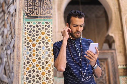 Smiling Arab man listening to music. About 25 years old, Middle Eastern male.