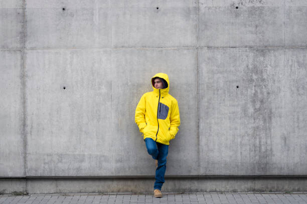 istock Young male rest on the wall with yellow coat looking at left 878508196