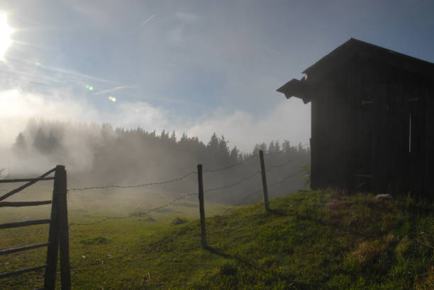 Fog in front of a barn and a fence on the mountain Schöckl near Graz, Austria