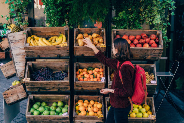 Woman choosing fresh fruits on the street of Florence Young Caucasian woman choosing fresh fruits on the street of Florence market stall stock pictures, royalty-free photos & images
