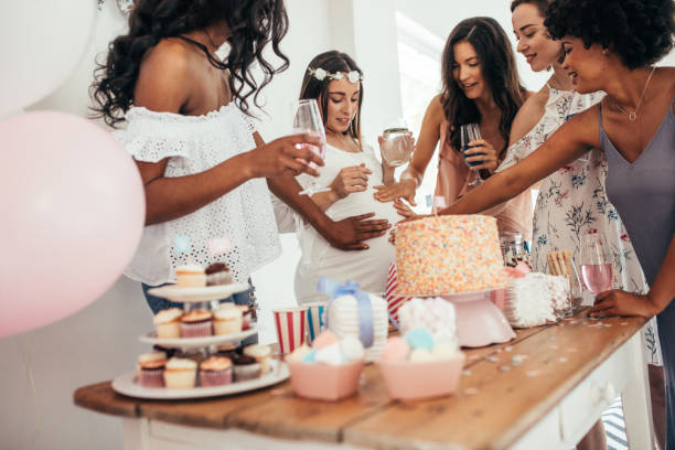 Friends sharing love and support to pregnant woman Group of female friends touching tummy of a pregnant woman at a baby shower. Female friends sharing love and support to pregnant woman. baby shower party stock pictures, royalty-free photos & images