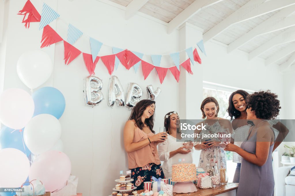 Pregnant woman celebrating baby shower with friends Group of multiracial women at a baby shower. Pregnant woman celebrating baby shower with female friends at home. Baby Shower Stock Photo