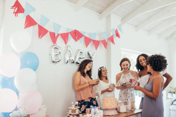 Pregnant woman celebrating baby shower with friends Group of multiracial women at a baby shower. Pregnant woman celebrating baby shower with female friends at home. baby shower stock pictures, royalty-free photos & images
