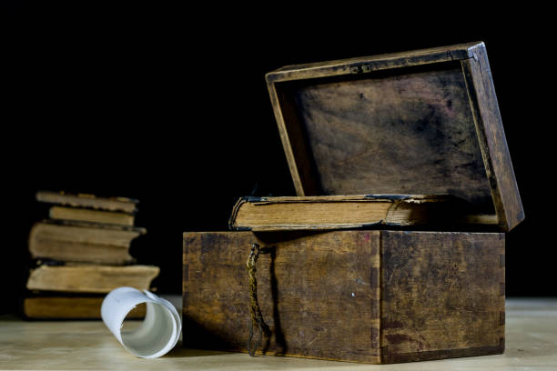 Old rolls and plans in folded paper rolls. Old book and case. Documents on an old wooden table. Black background.