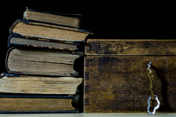 istock Old rolls and plans in folded paper rolls. Old book and case. Documents on an old wooden table. Black background. 878636402