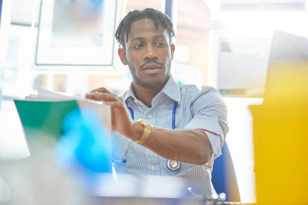 istock Junior doctor organising his patient's paperwork 878644592
