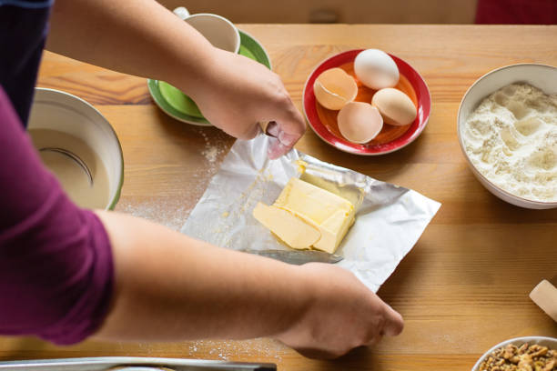 istock Female hands opening a butter packaging, ingredients on the table 878650526