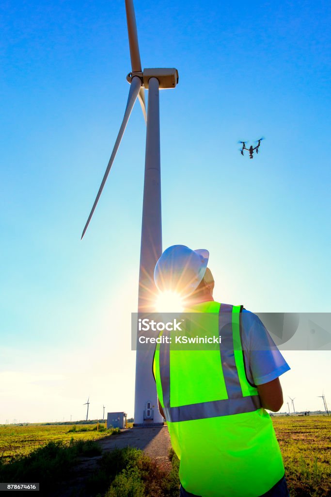 Drone Pilot Operating UAV During Wind Turbine Inspection Drone pilot wearing his safety vest operating a UAV on Kansas wind farm. Drone Stock Photo