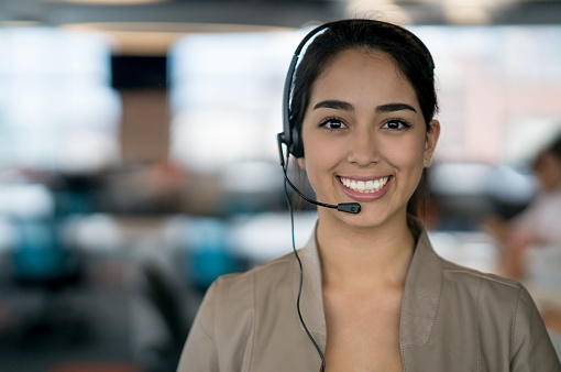 Portrait of a happy Latin American woman working at a call center and looking at the camera smiling
