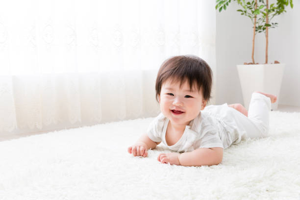 азиатский ребенок в гостиной - baby lying down indoors one person стоковые фото и изображения