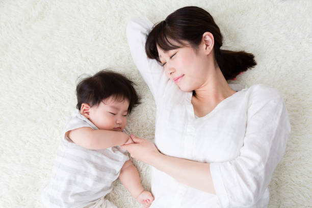 asiatische mutter und baby im wohnzimmer - sleeping child mother family stock-fotos und bilder