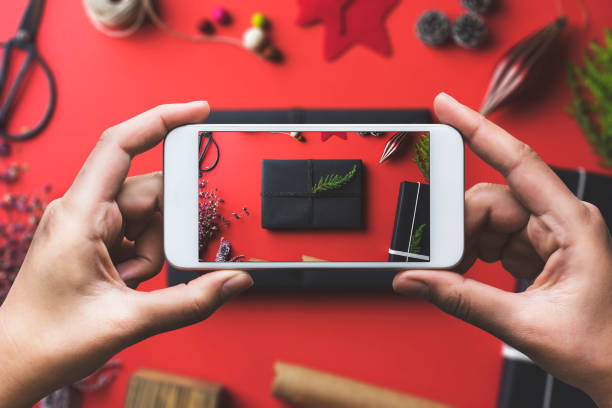istock Hand photographing Christmas gift flat lay on red background 878708904