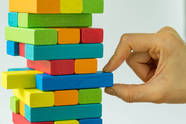 Hand pulling colorful wooden block from the tower as Business Risk or stability concept