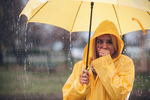雨と傘保持金髪女性の咳 - umbrella women storm yellow ストックフォトと画像