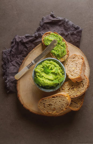 istock Baguette with mashed green peas and mint. Dark background. Selective focus. Top view 878717716