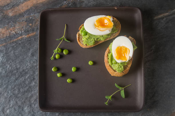 istock Baguette with mashed green peas, eggs and mint. Dark background. Selective focus. TOp view 878717850