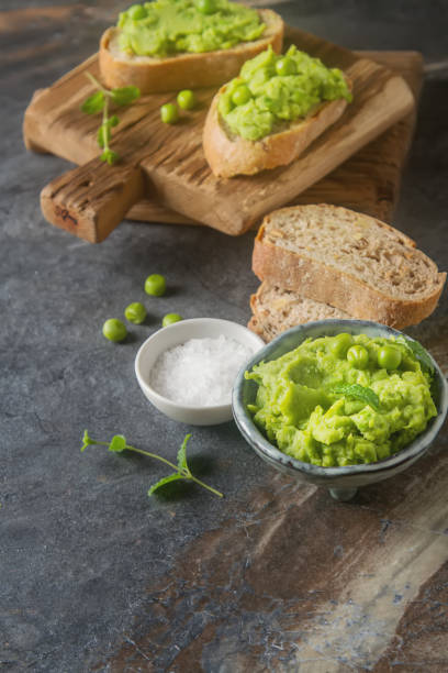 istock Baguette with mashed green peas and mint. Dark background. Selective focus. Top view 878717872