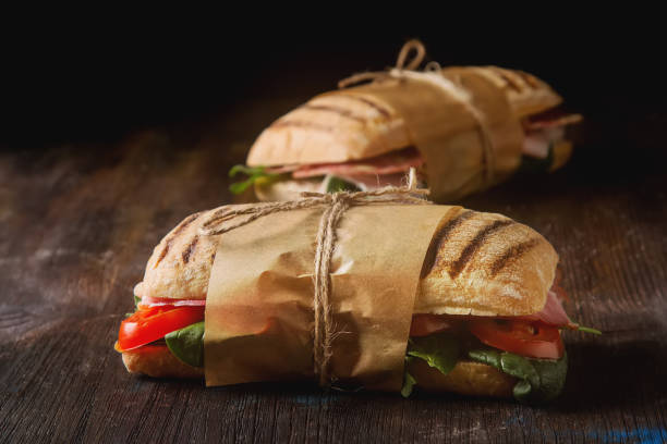 istock French baguette with sausage, tomatoes and lettuce. Dark background. 878718476