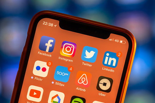 Social media app icons on modern new smartphone display close-up around other iphone applications