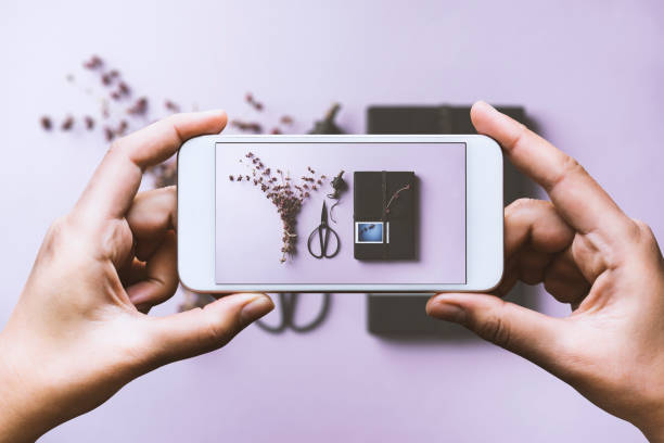 istock Hand photographing black gift box flat lay on purple background 878737054