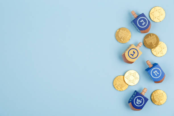 fondo azul con dreidels multicoloras y monedas de chocolate. hanukkah y concepto de la fiesta judía. - judaísmo fotos fotografías e imágenes de stock