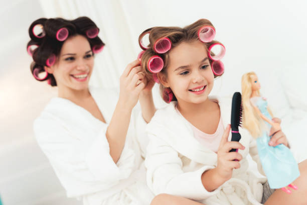 istock Mom combs her little daughter while she makes the doll's hairstyle. 878761240