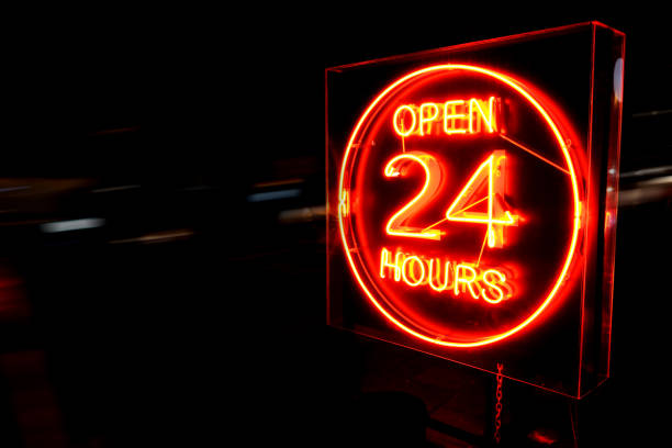 25 Hours neon sign. Open 24 Hours neon sign on the road side at night with moving cars. convenience stock pictures, royalty-free photos & images