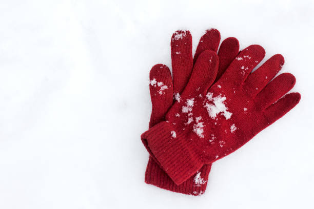 Playful Winter. Gloves lying on snow background .
