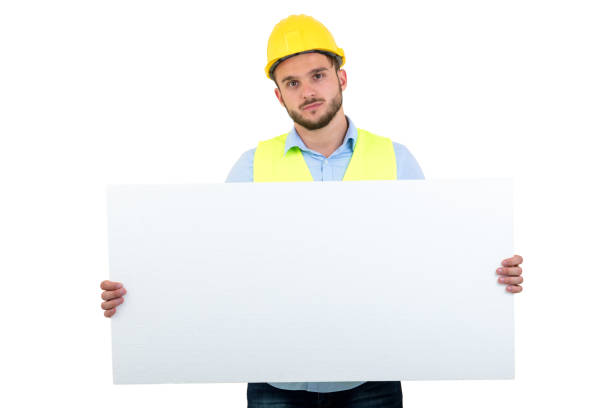 istock Happy male engineer holding an advertisement blank banner. Isolated on white background 878782068