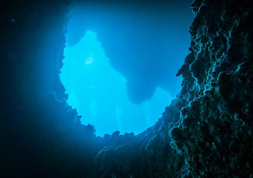 The underwater scuba diver point of view from within a submerged cave system.   Cave diving is notoriously difficult and dangerous, requiring specialist training.  This image was taken at a famous dive site called ‘The Cathedral’ in Ko Haa, Andaman Sea, Krabi, Thailand.