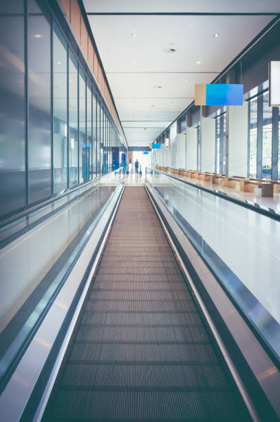 istock Modern long walkway of escalator moving forward at airport terminal. 878789432