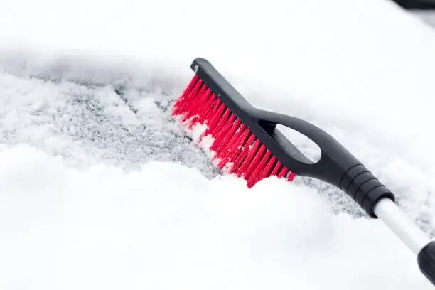 Photo of Transportation, winter, weather, people and vehicle concept - man cleaning snow from car with brush .