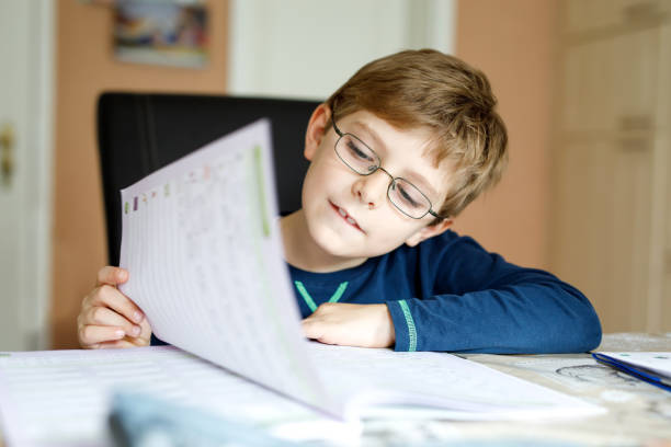 istock Happy school kid boy at home making homework 878812104