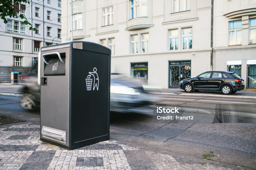 A modern smart trash can on the street in Prague in the Czech Republic. Collection of waste in Europe for subsequent disposal. Eco-friendly waste collection. In the background the car is in motion. A modern clever trash can on the street in Prague in the Czech Republic. Collection of waste in Europe for subsequent disposal. Eco-friendly waste collection Garbage Bin Stock Photo