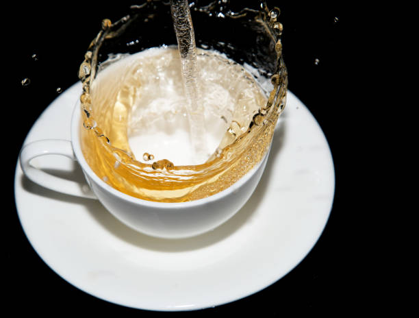 istock tea being poured into a saucer with splashes on a black background 878820094