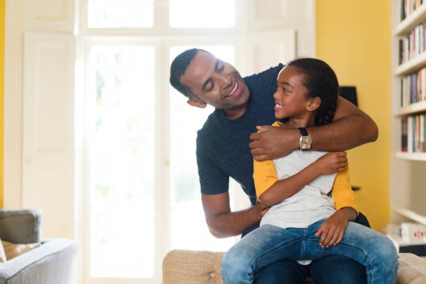 istock Happy father and daughter sitting on sofa at home 878831046