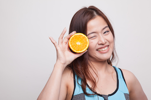 Asian healthy girl on diet with orange fruit on white background
