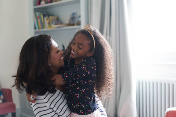 istock Mother looking daughter while embracing at home 878840858