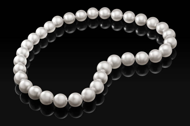 istock Luxury white pearl necklace on a black background with glossy reflection 878843648