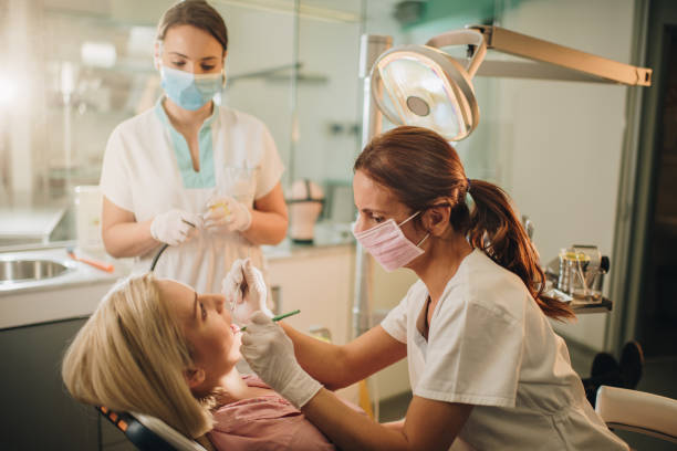 istock Dentist and dental assistant examining woman's teeth during dental appointment. 878852670