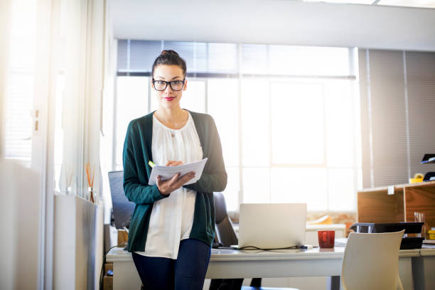istock Young businesswoman holding documents in office 878857620